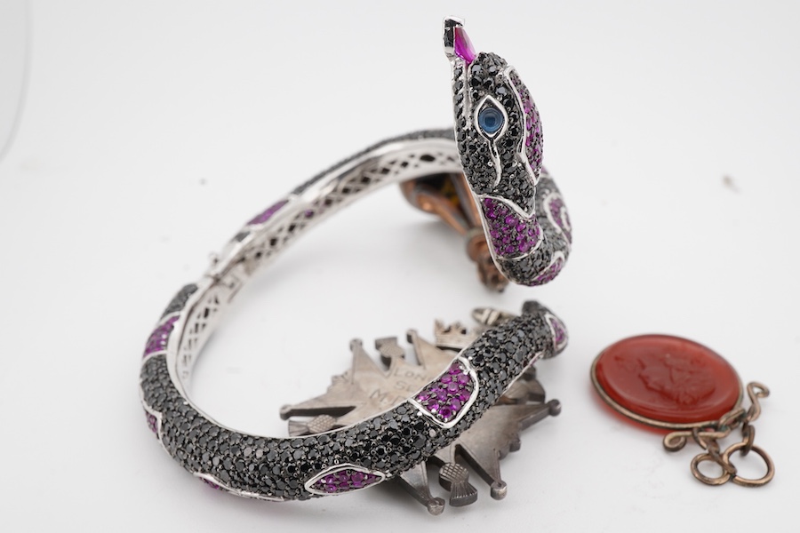 A collection of jewels including a snake bracelet, comprising: a hinged bangle modelled as a snake in silver, pavé-set with circular-cut black sapphires and synthetic rubies, its tongue a marquise-shaped synthetic ruby,